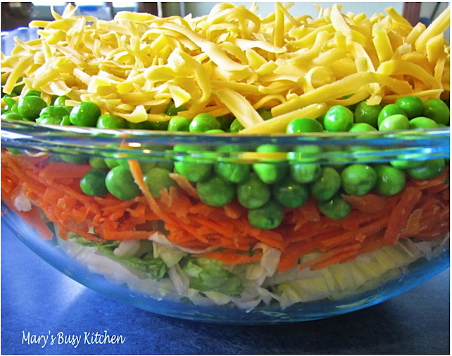 Easy layered salad with carrots, peas, cheese, and bacon